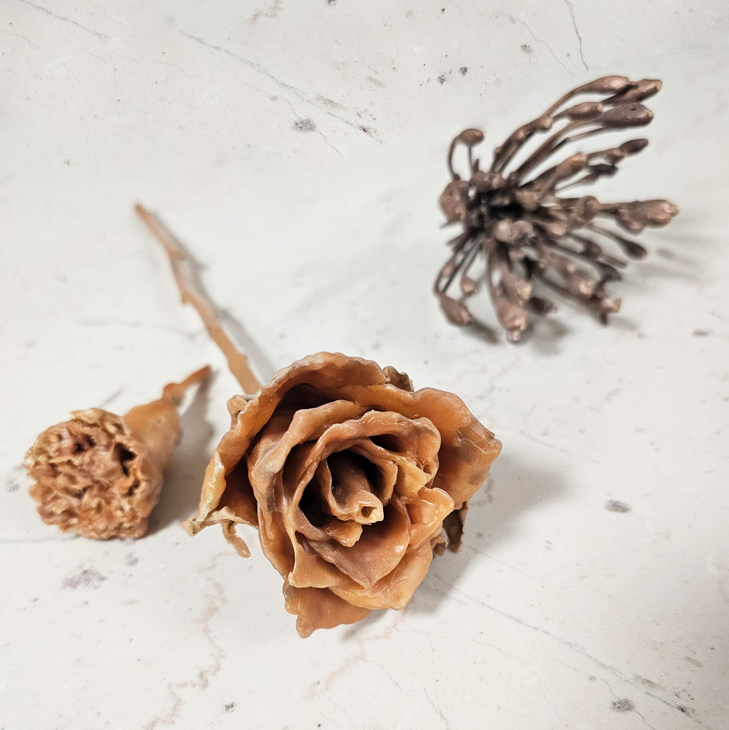 rouwbloem bloem in brons en twee bloemen in was, waaronder een roos