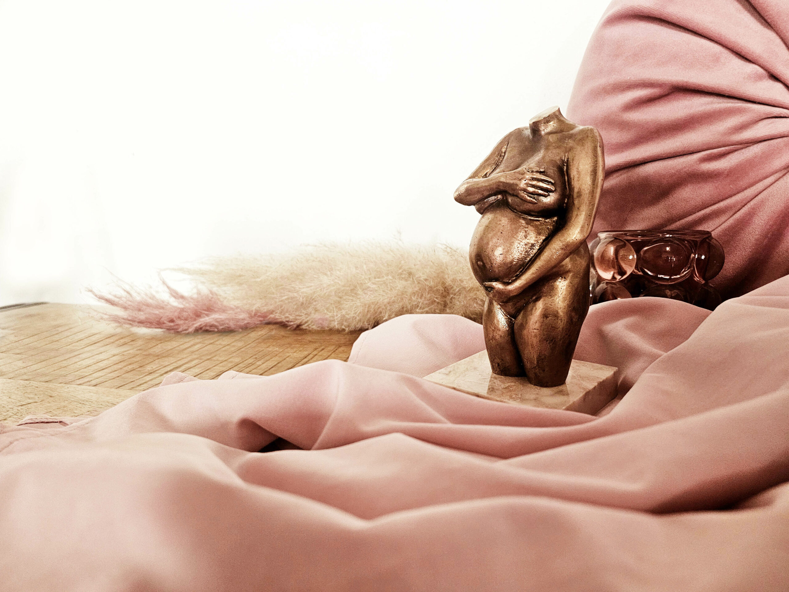 Zwangerschapsbeeldje in brons met roze achtergrond