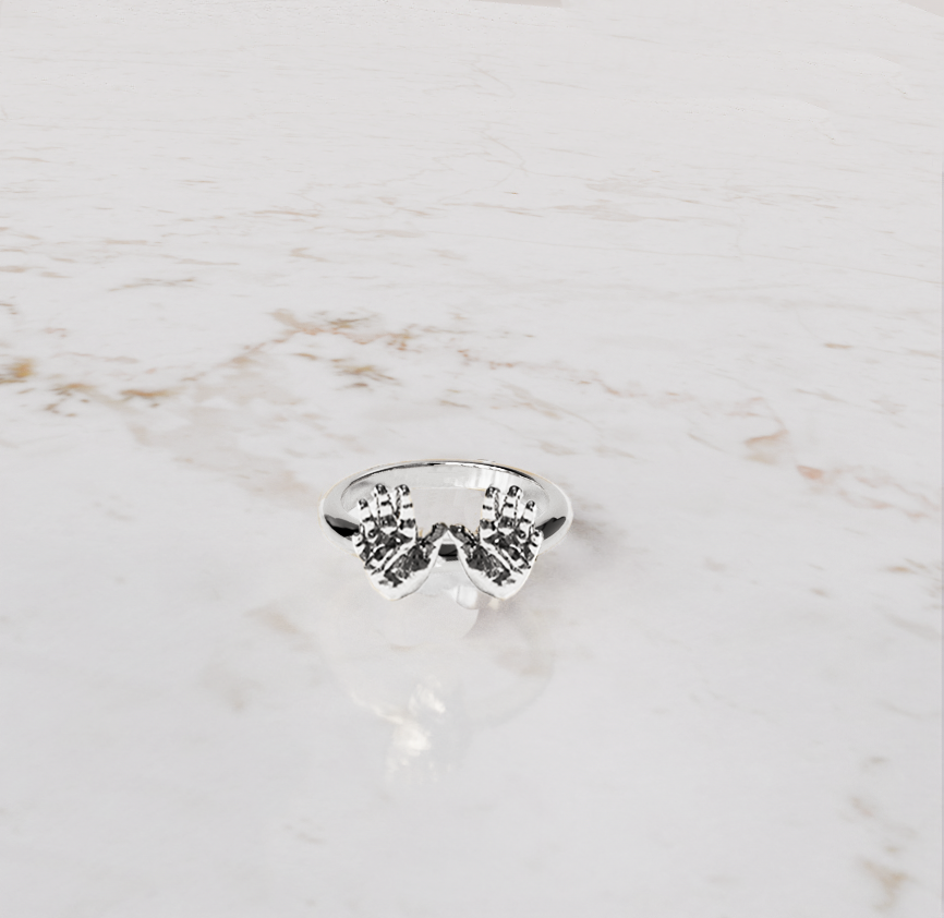 babyhandjes in zilveren ring