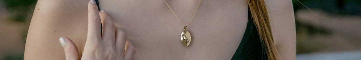 Gepersonaliseerde ketting met ovale hanger met voetstapjes in het goud gedragen door een model